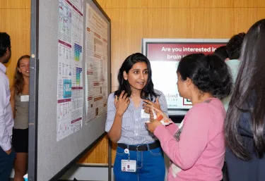 Marwa Zafarullah talks about her research poster with another person.